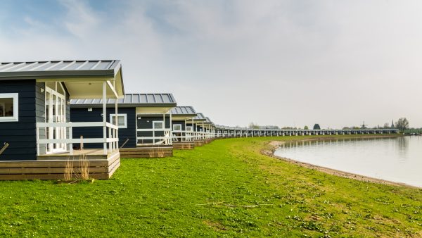 Identical wooden modular cabins surround the edge of a lake