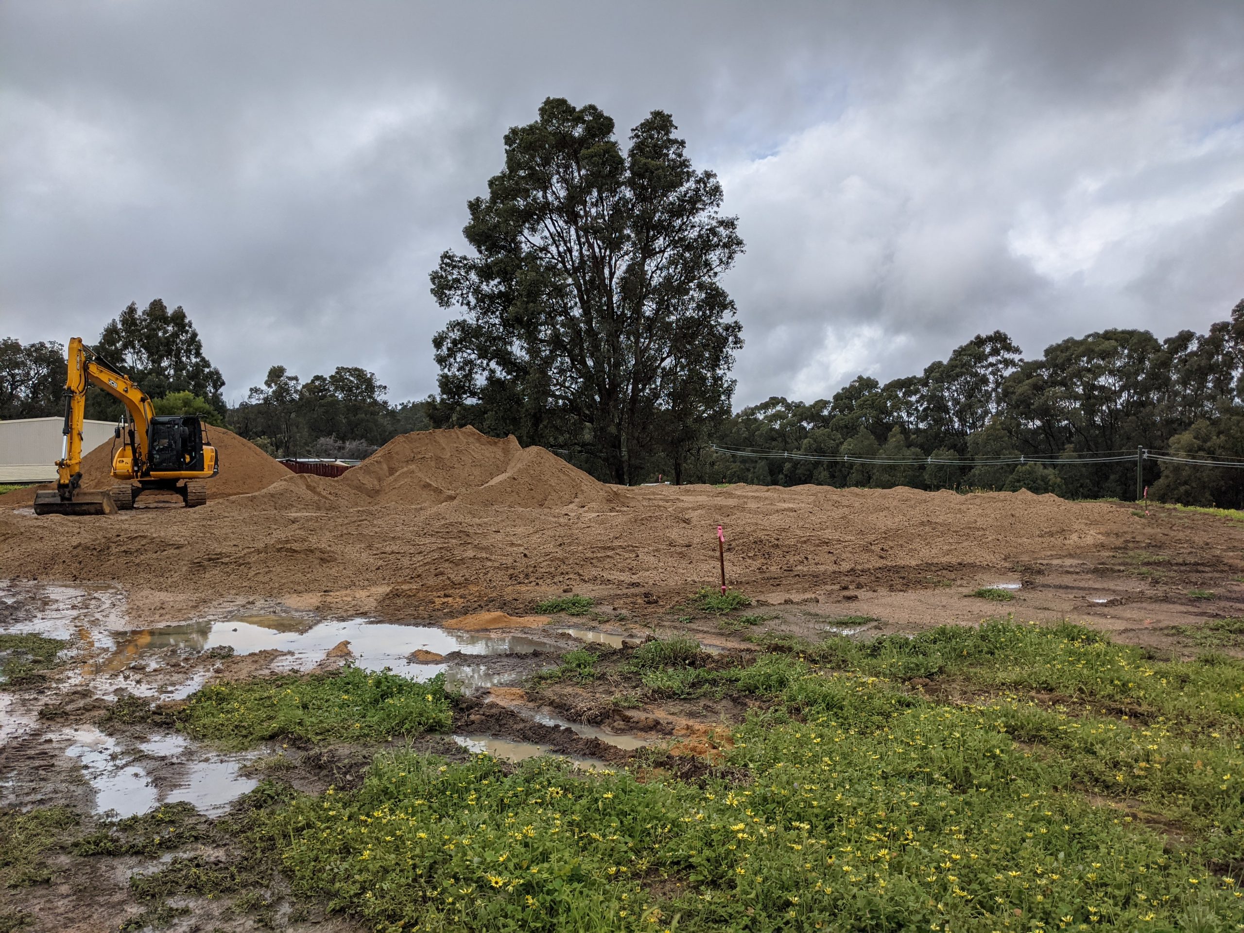 An excavator works on levelling a sand pad for module installation