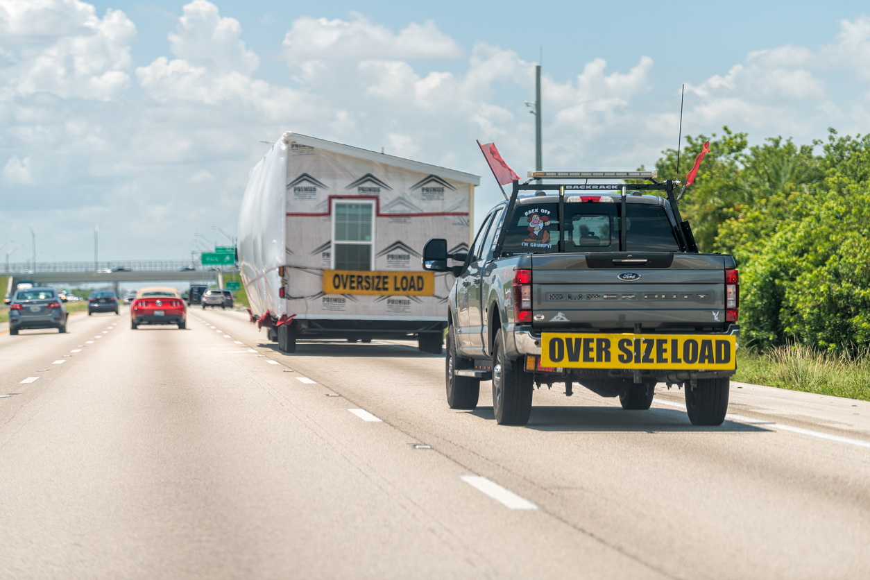 Truck transporting an oversized load prefab building