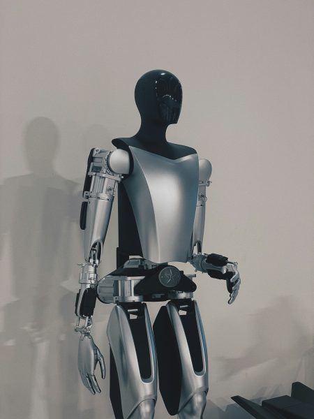 A sleek humanoid robot with a glossy black head and metallic silver body stands against a plain background, showcasing advanced robotics technology