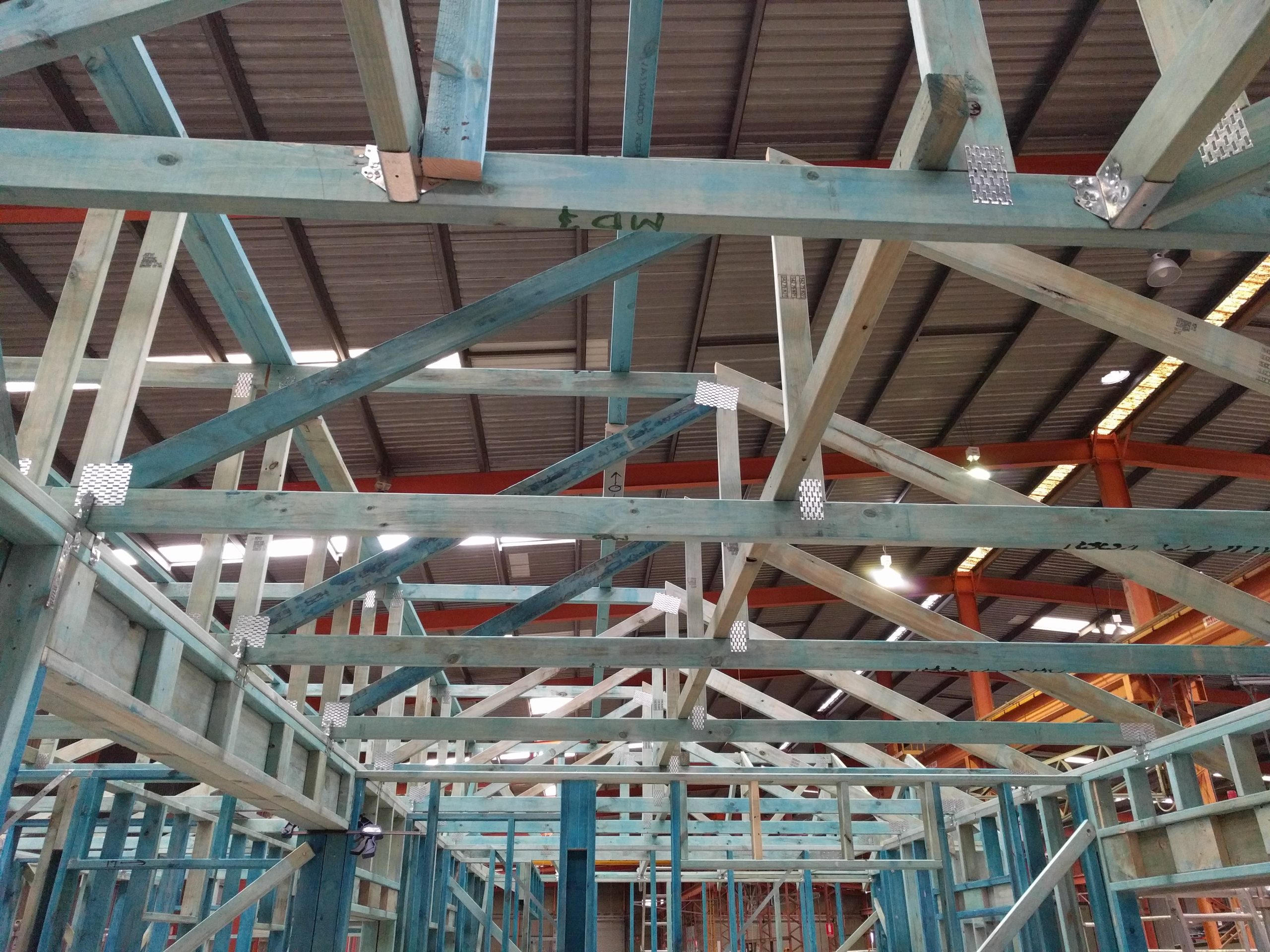 Timber truss framing underway in a factory setting for a modular home build, demonstrating precision and ideal conditions